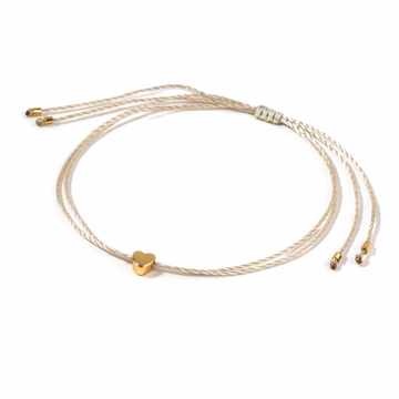 Gold bracelet with a heart charm on a white background